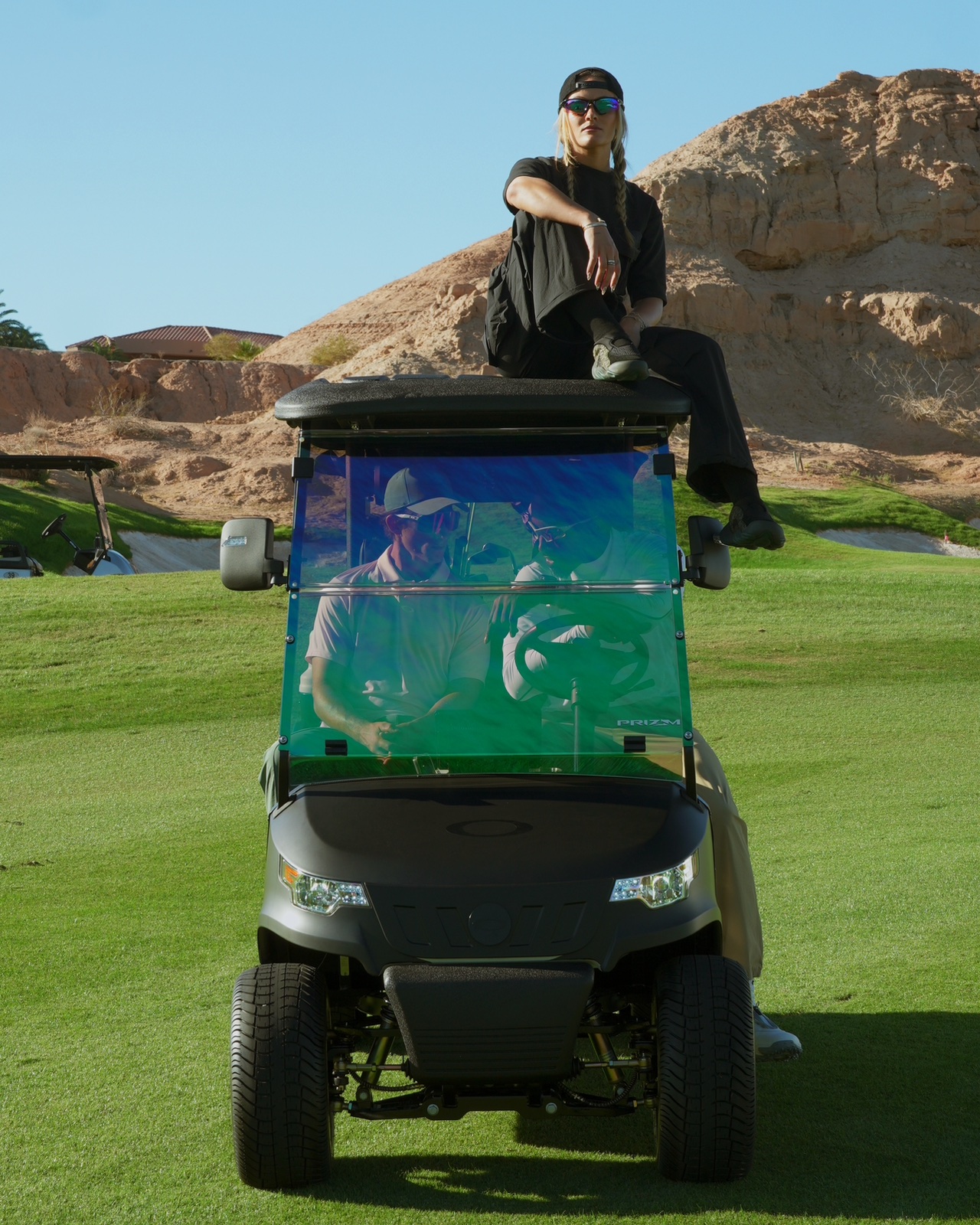 Golfer seated on a golf cart against desert rock during an Oakley shoot.