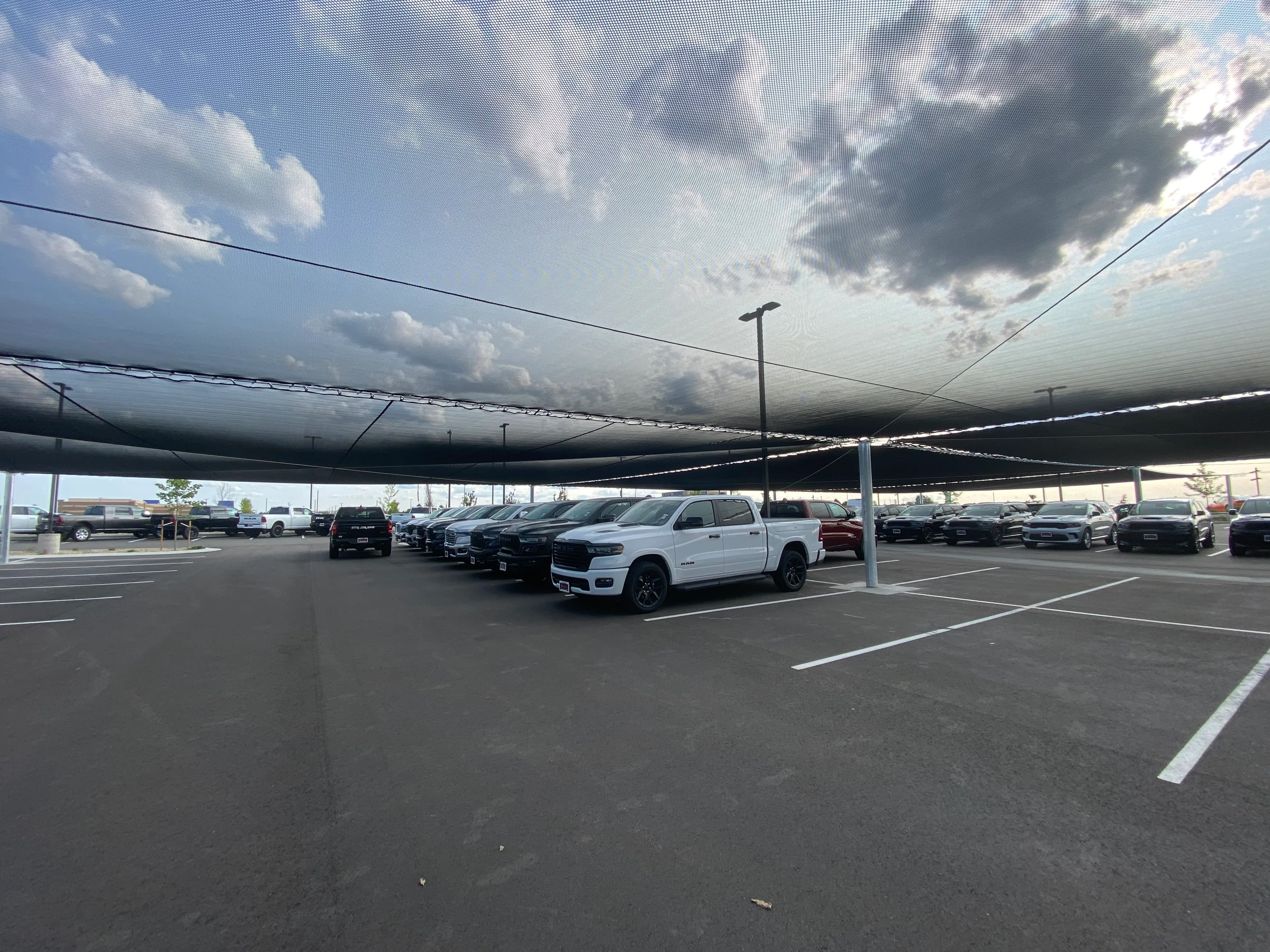 Hail net over a parking lot with trucks and other vehicles visibile