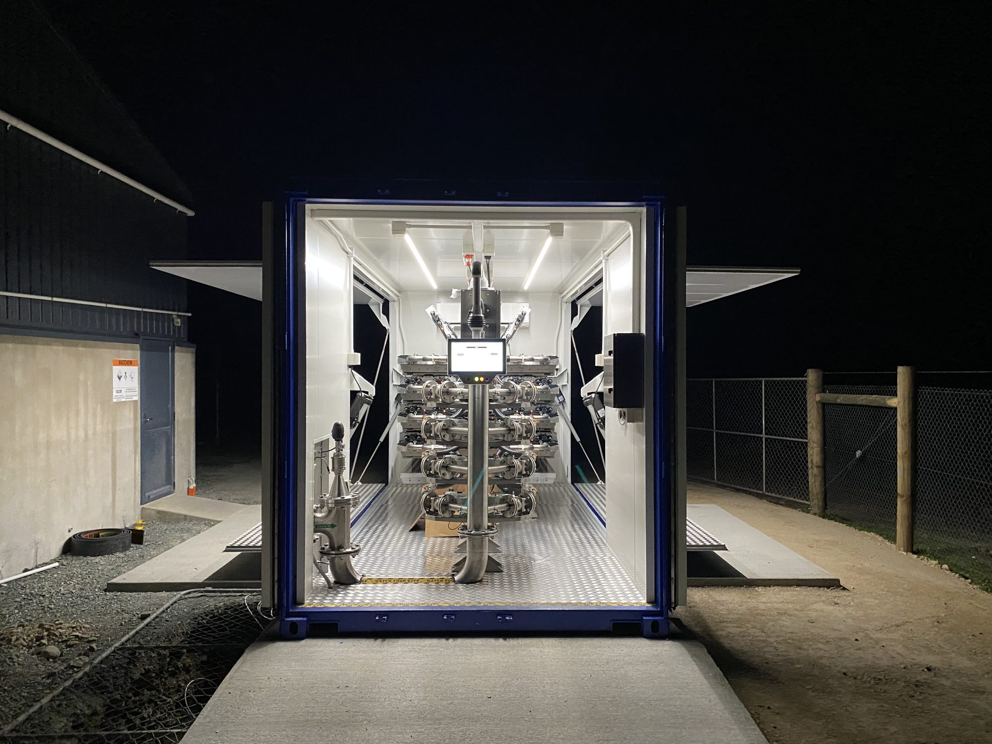 A containerised disinfection system lit up at night on site