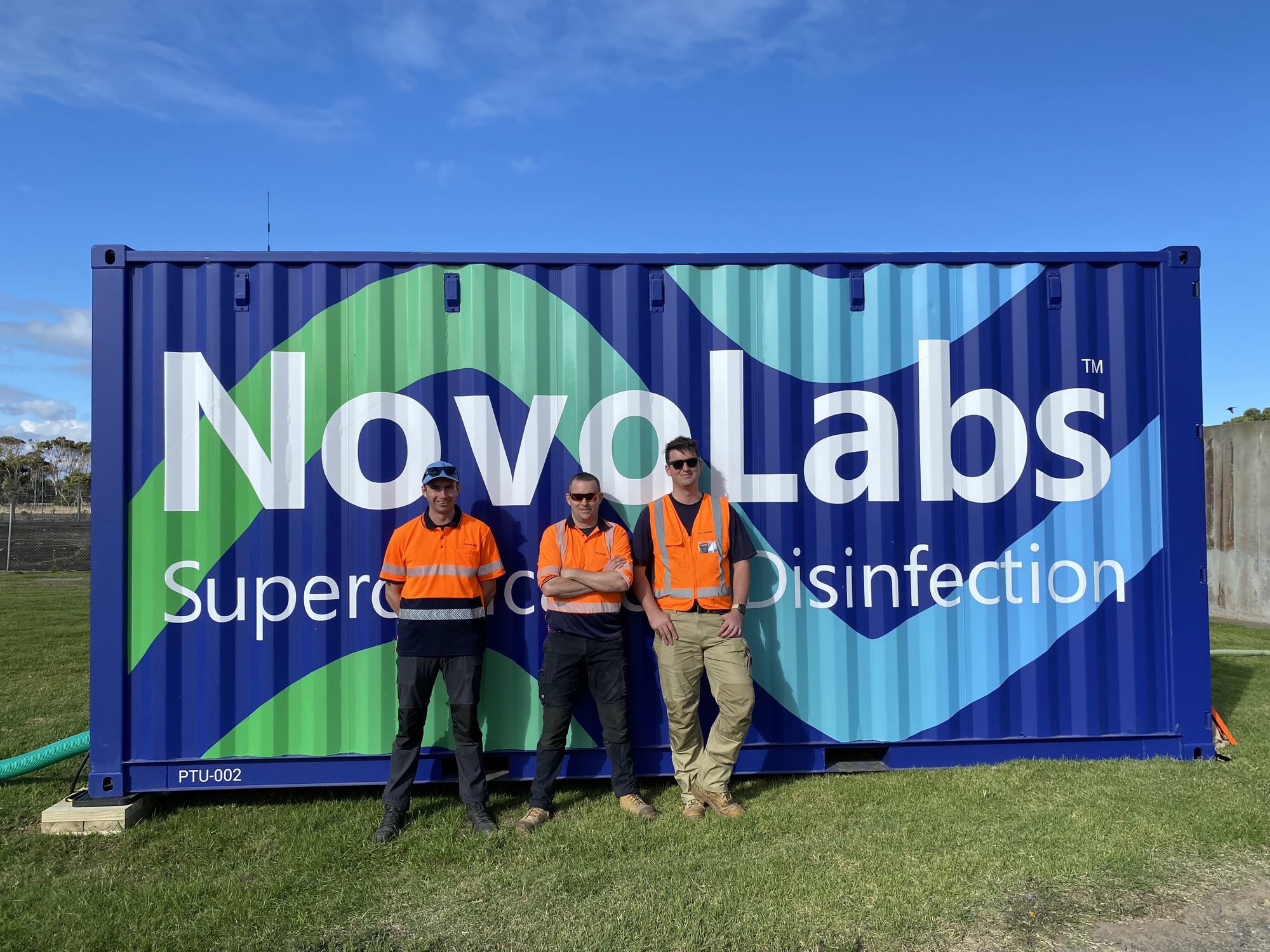 Two team members in front of an installed disinfection system