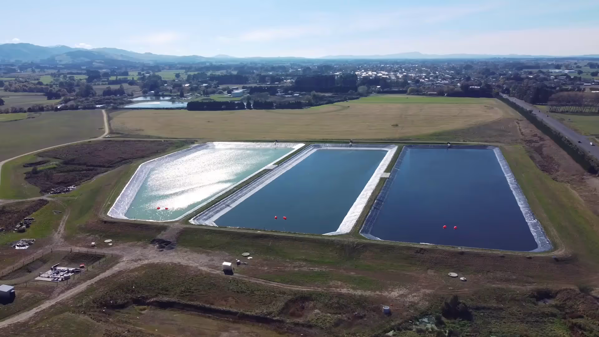 NovoLabs staff explaining the treatment process beside a wastewater pond