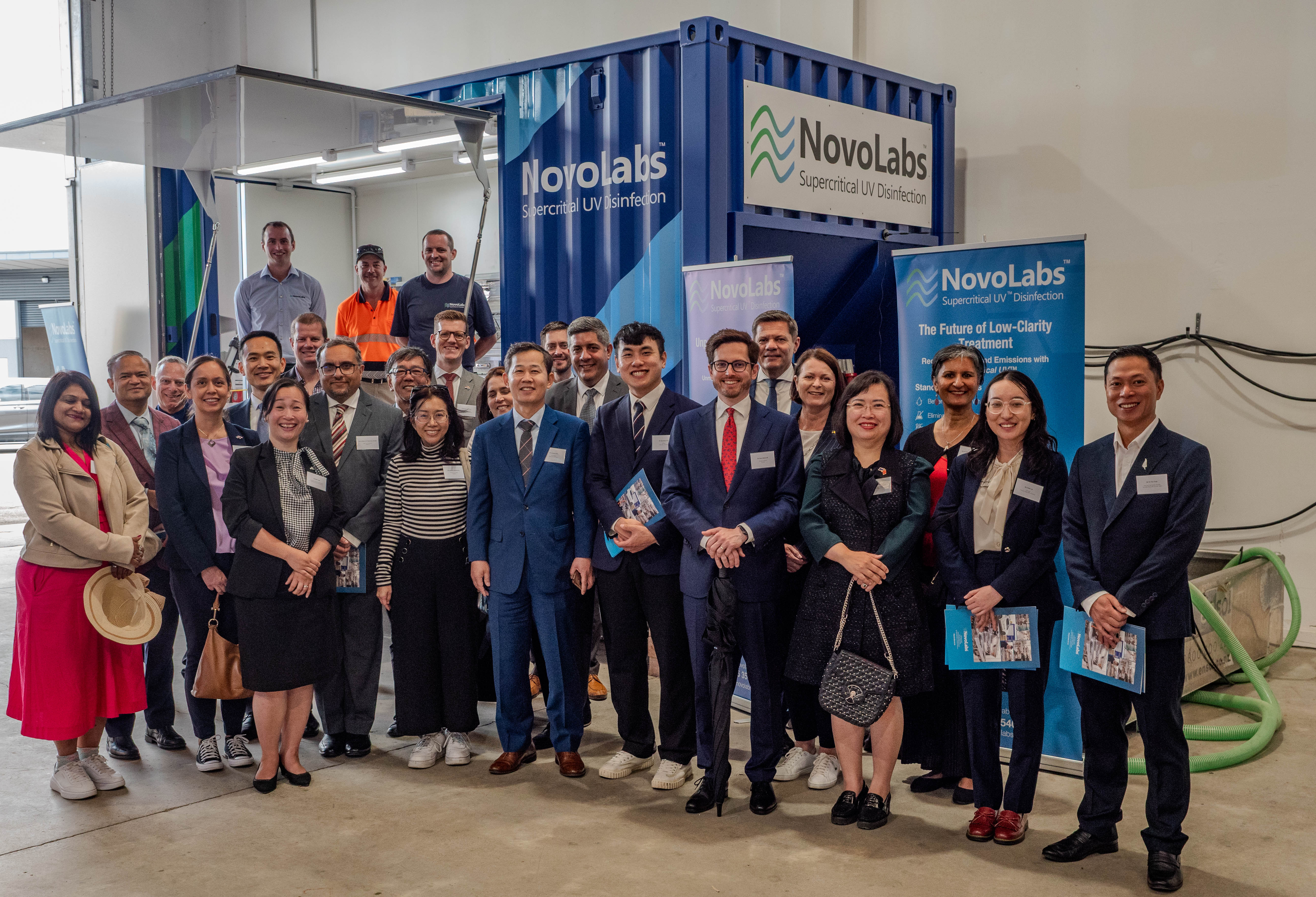 Group of diverse professionals posing in front of NovoLabs container for supercritical UV disinfection.