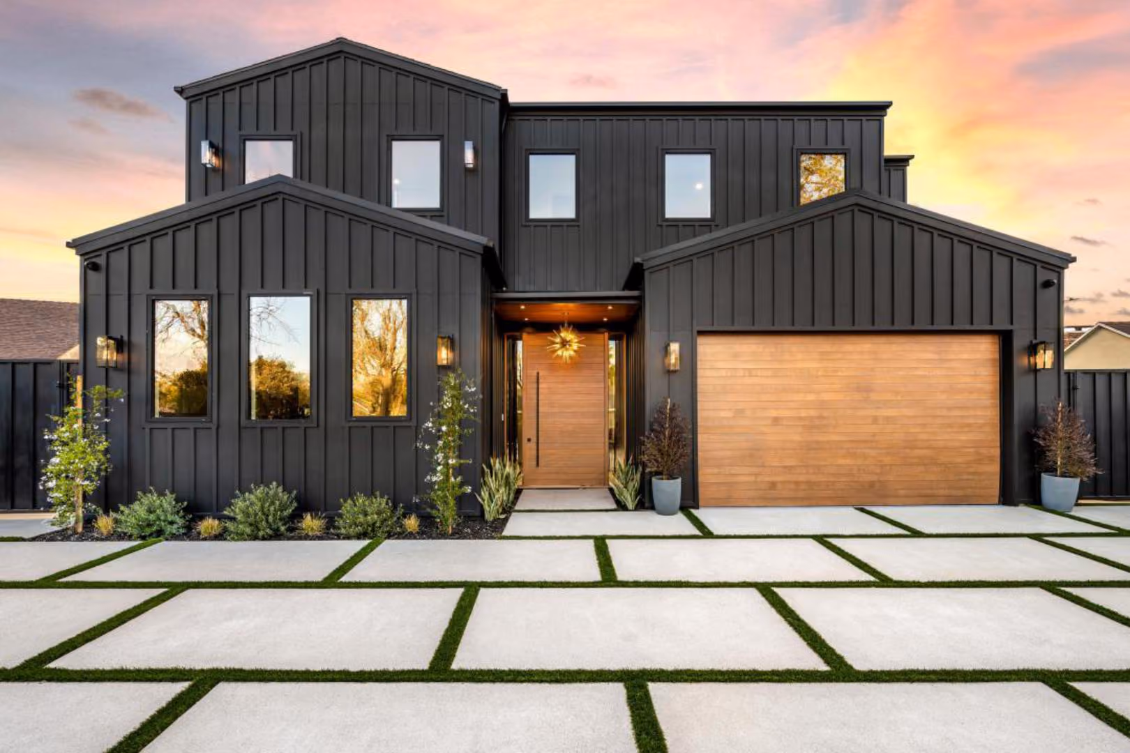 Renovated two-story home with black board-and-batten siding and wood garage door