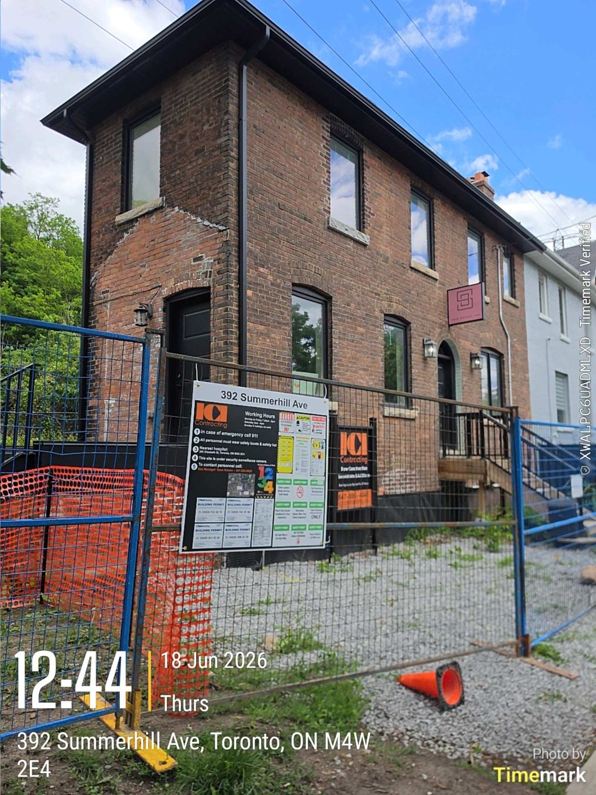 Front of a Toronto brick home with construction fencing and permit board