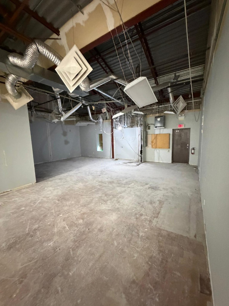 Stripped unit with ceiling removed and ductwork exposed for the medical clinic conversion