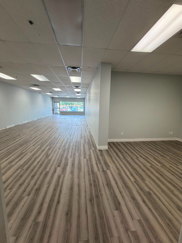 Empty unit with vinyl floor and ceiling grid ready for the medical clinic fit-out