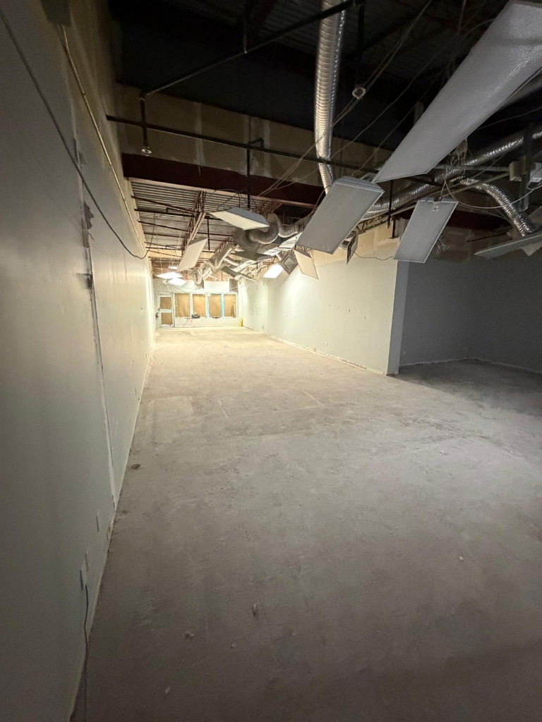 Bare concrete floor and open ceiling in the stripped medical clinic unit