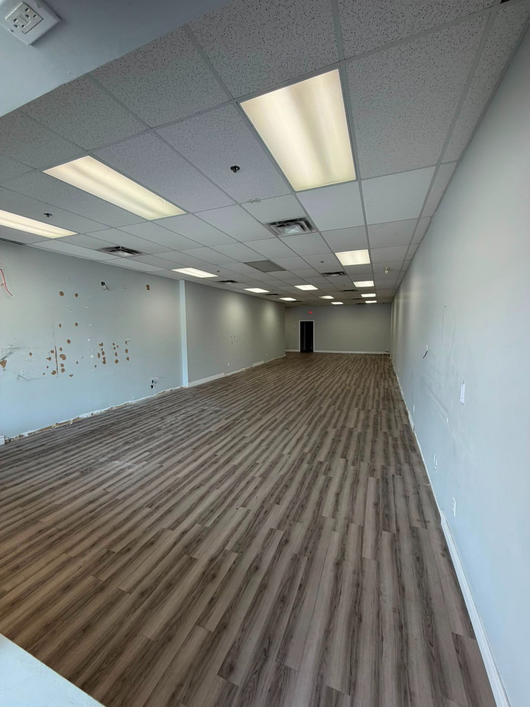 Long empty unit with vinyl plank flooring after the showroom was removed
