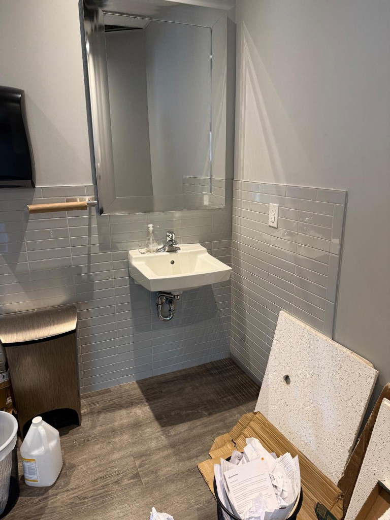 Washroom sink and mirror with materials on the floor in a North York clinic fit-out