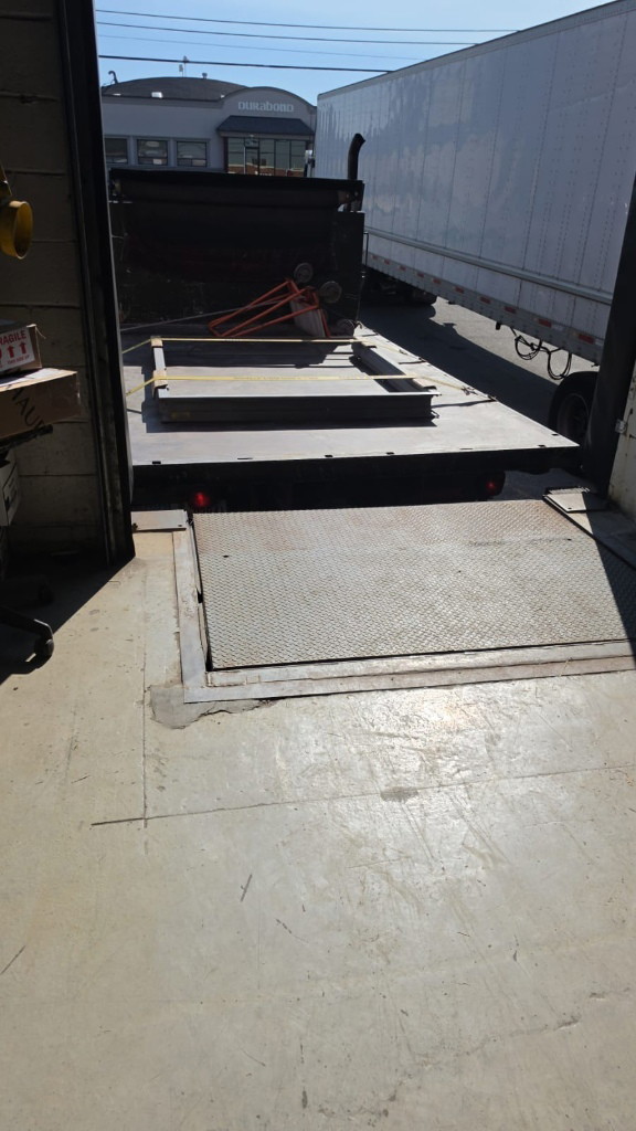Loading dock with a steel dock leveler beside a parked trailer at a Scarborough facility