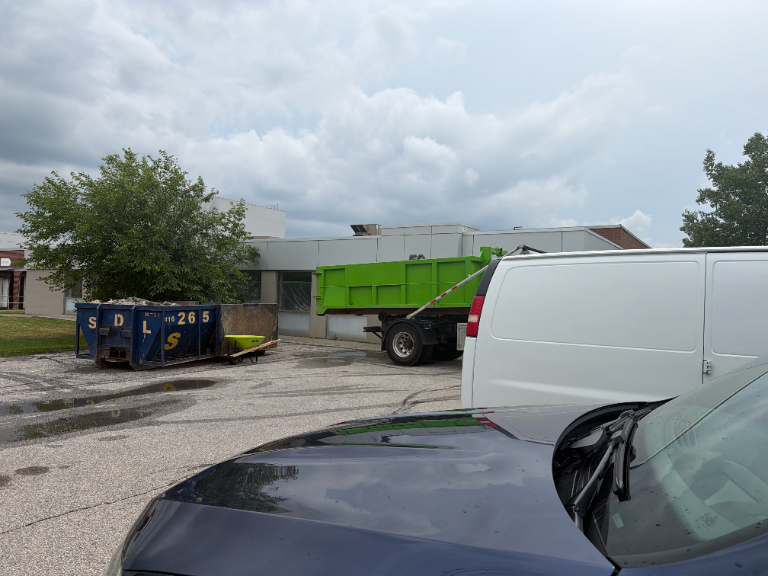Waste bins and a roll-off truck in the parking lot of a Scarborough commercial facility