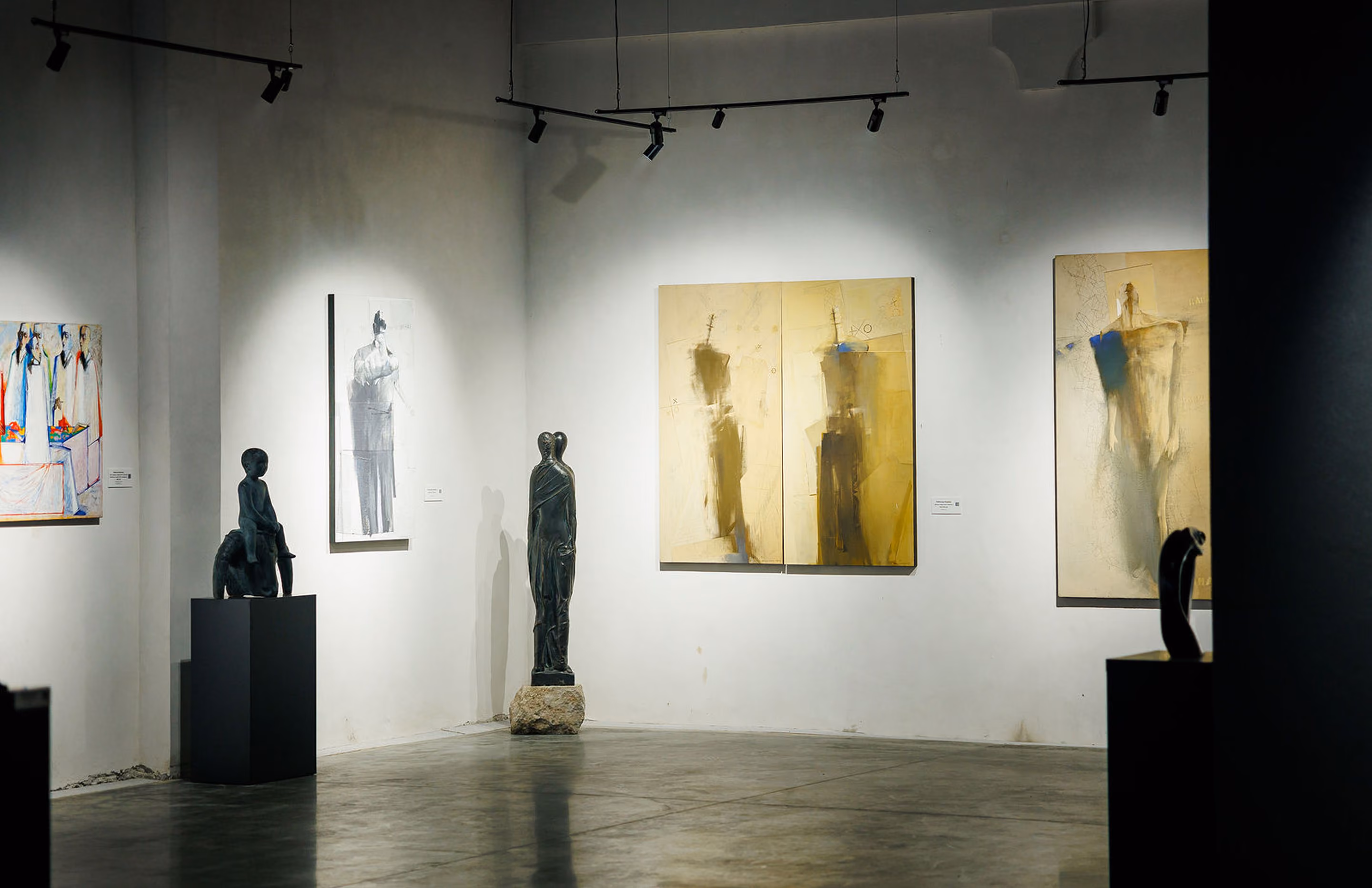 Modern art gallery space with abstract paintings on white walls and bronze sculptures on pedestals.