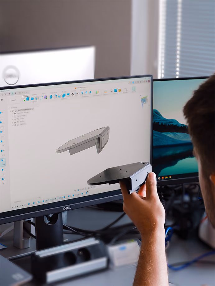Muž u monitoru s 3D modelem Technik kontroluje 3D model dílu na firemním počítači