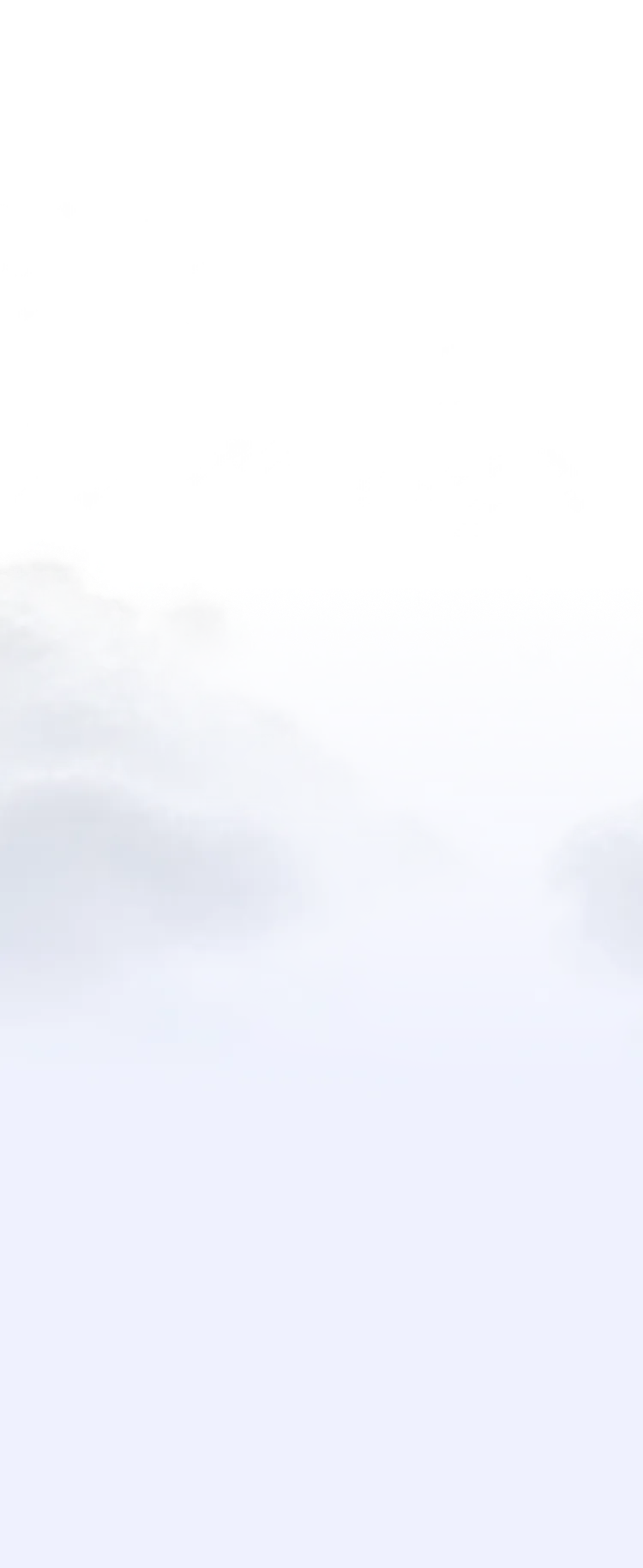 Foggy mountain peaks emerging above low-hanging clouds under a blue sky.