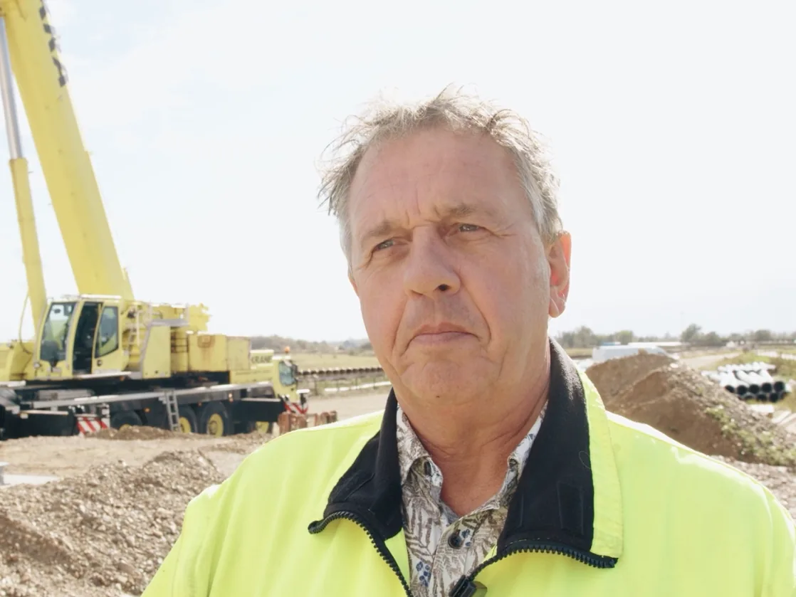 Wim Verschuren, Production Director at Steengoed, in a high-visibility jacket at a construction site with a mobile crane behind him