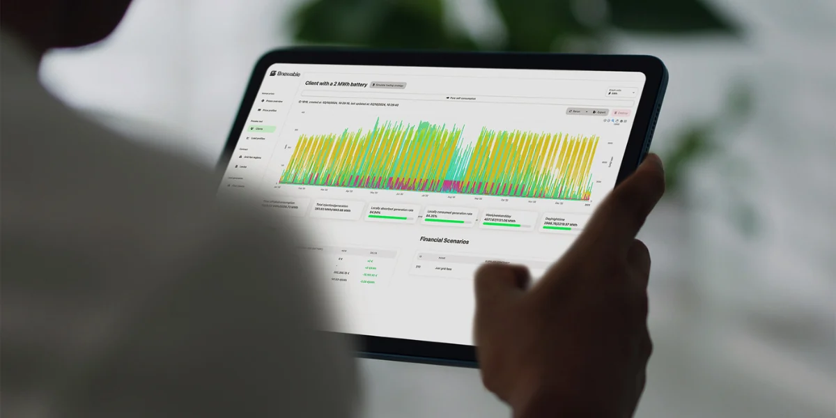 A hand pointing at a Bnewable Voltana dashboard on a tablet, showing a year of battery charge and discharge data alongside financial scenarios