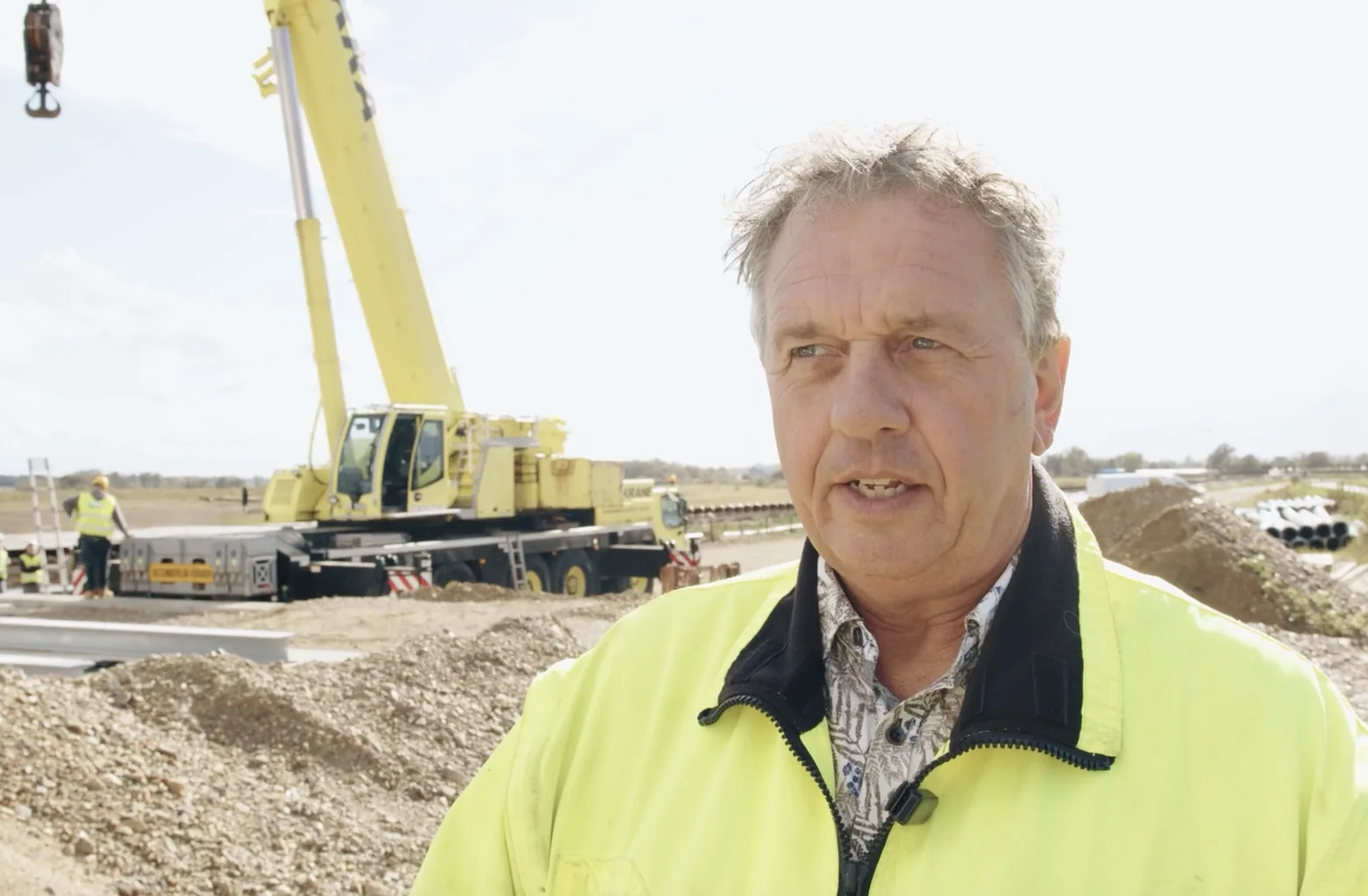 Wim Verschuren, Production Director at Steengoed, in a high-visibility jacket on a construction site with a mobile crane behind him