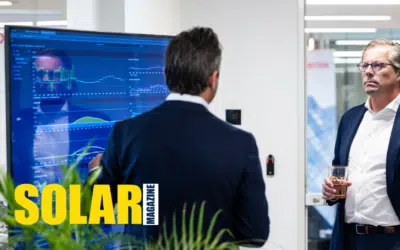 Two Bnewable colleagues discussing an energy dashboard on a large screen in the office, with the Solar Magazine logo