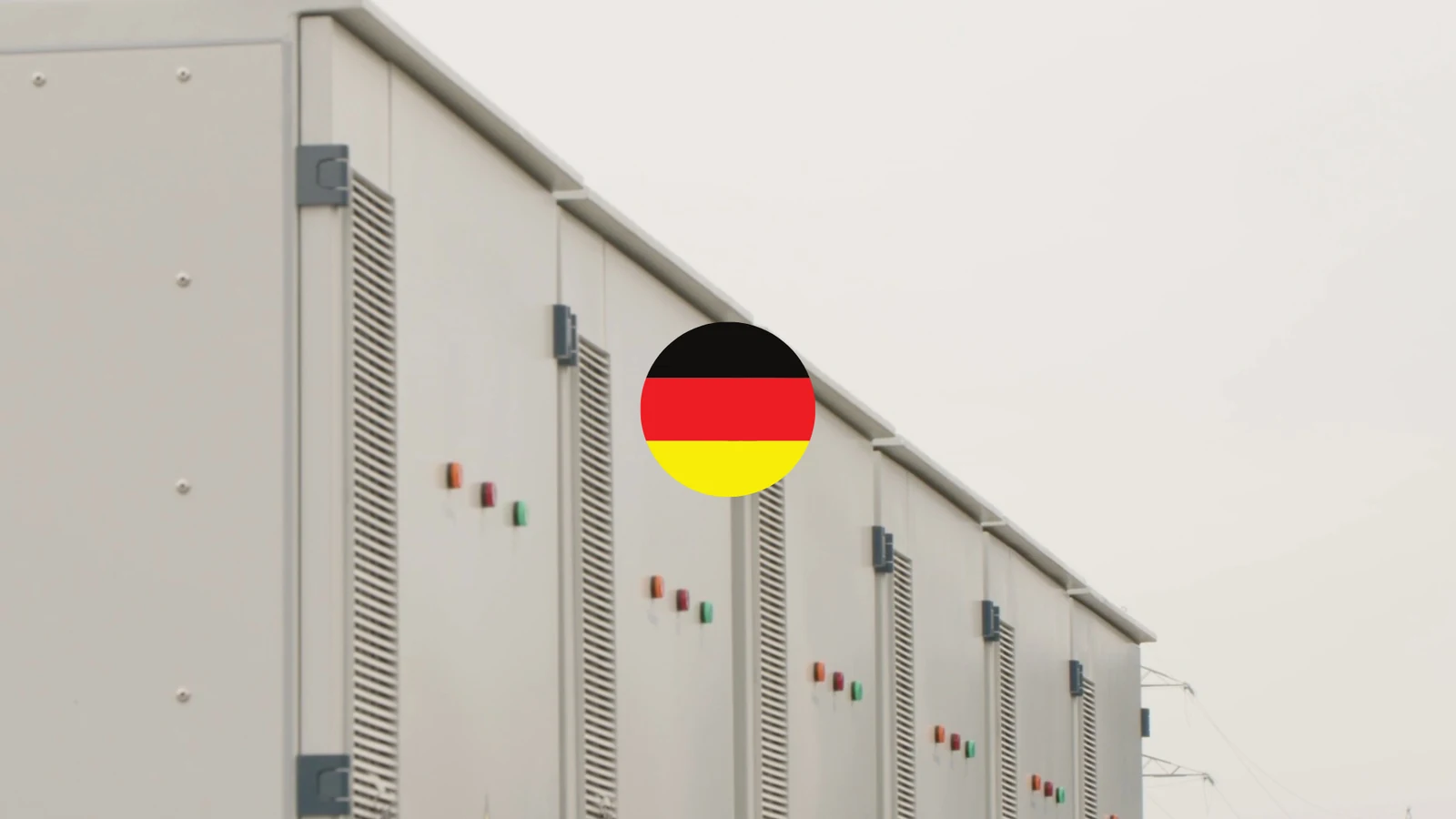 Row of Bnewable battery storage containers under a pale sky, with a circular German flag marking the entry into the German market
