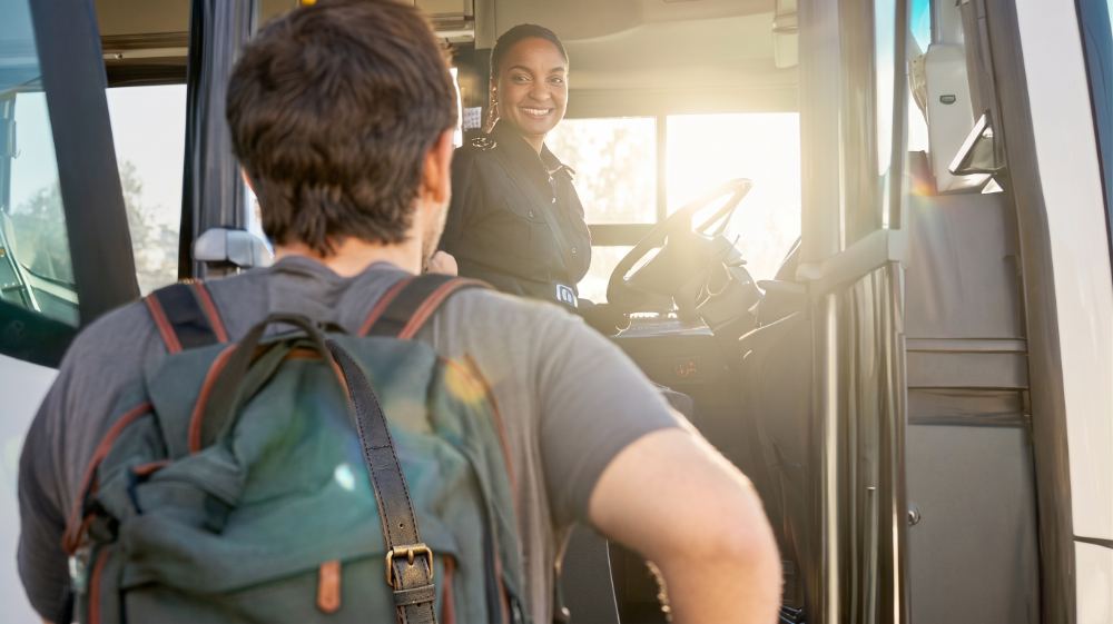 A coach driver greeting a guest boarding at the door