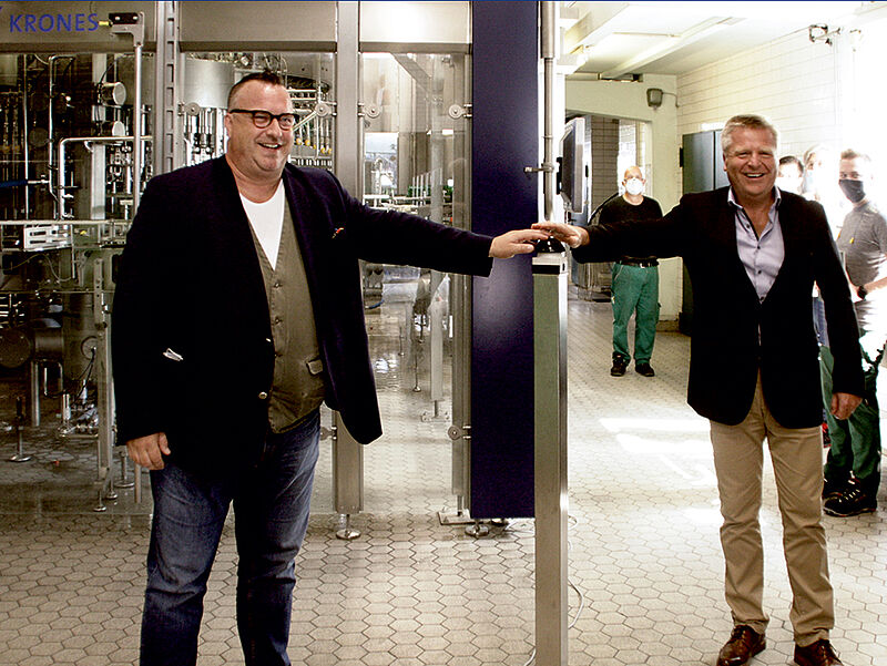 Staatssekretär Andy Becht und Brauereichef Roald Pauli drücken den Startknopf der neuen Flaschenabfüllung