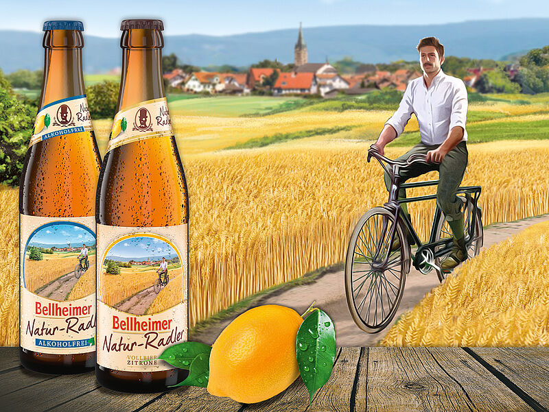 Zwei Flaschen Bellheimer Natur-Radler mit Zitrone vor einem Radfahrer im Weizenfeld