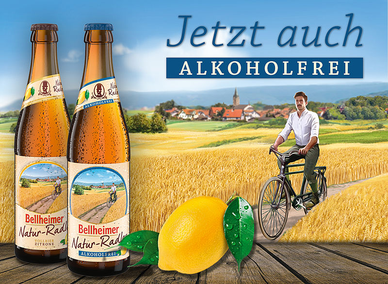 Zwei Flaschen Bellheimer Natur-Radler alkoholfrei mit Zitrone vor einem Radfahrer im Weizenfeld