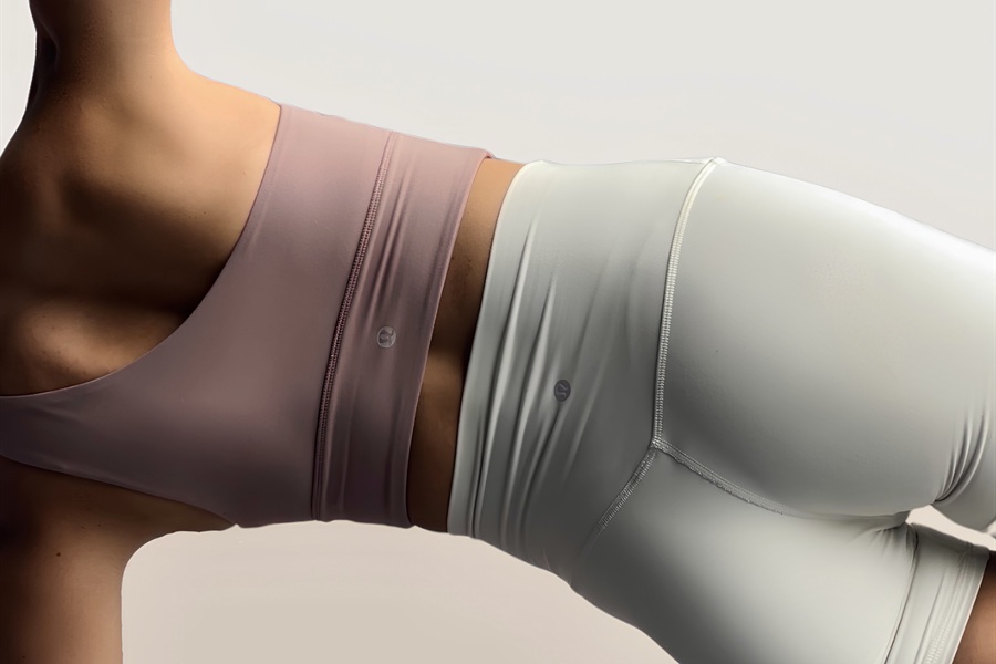 Close-up of a woman in activewear holding a plank position, shot side-on against a neutral backdrop.