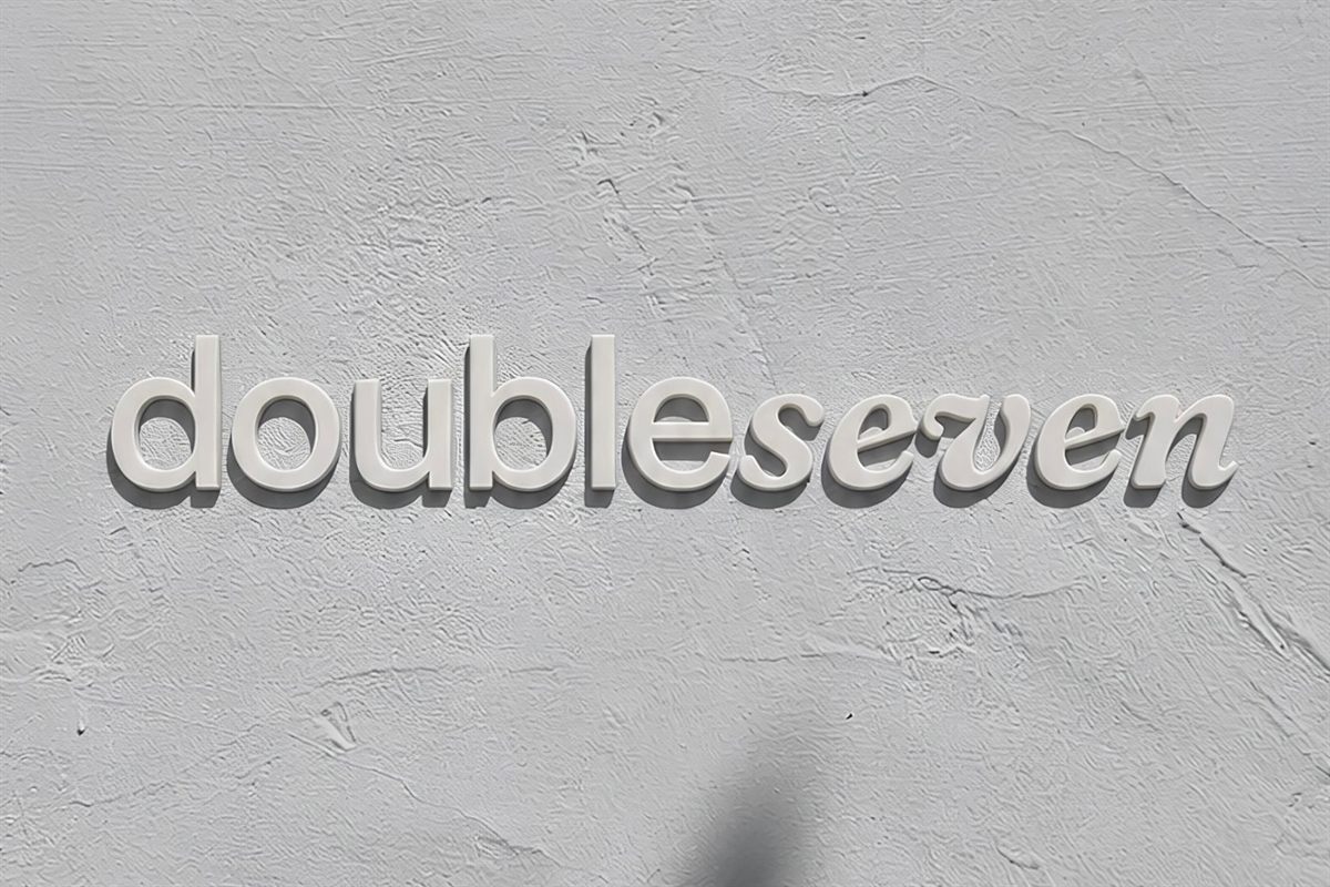 The doubleseven wordmark as raised lettering mounted on a textured pale grey wall