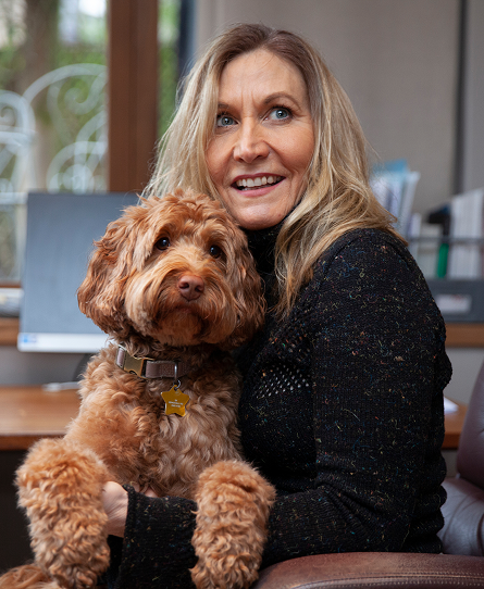 Harriet Young looking upwards, holding her cockapoo dog.