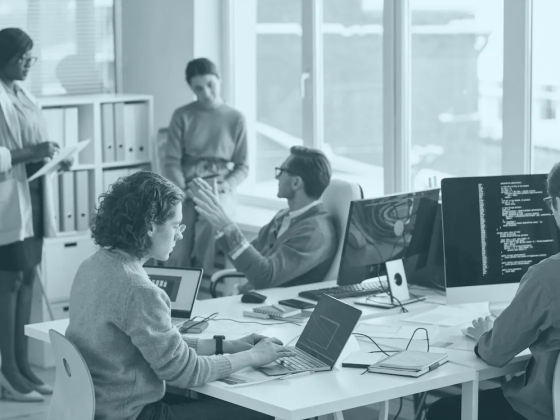 Un equipo pequeño trabajando en sus escritorios en una oficina luminosa