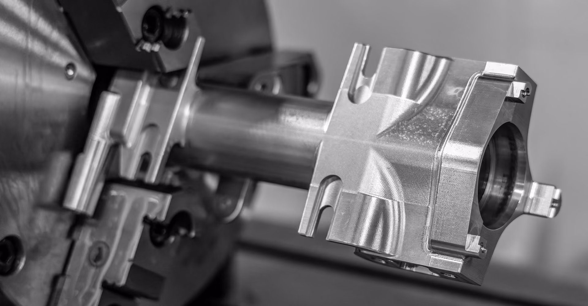 Precision-machined aluminum component held in a CNC machine during 4 and 5 axis machining.