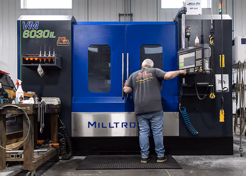 Operator using a Milltronics VM6030IL 4-axis CNC machining center at XL Pattern Shop.