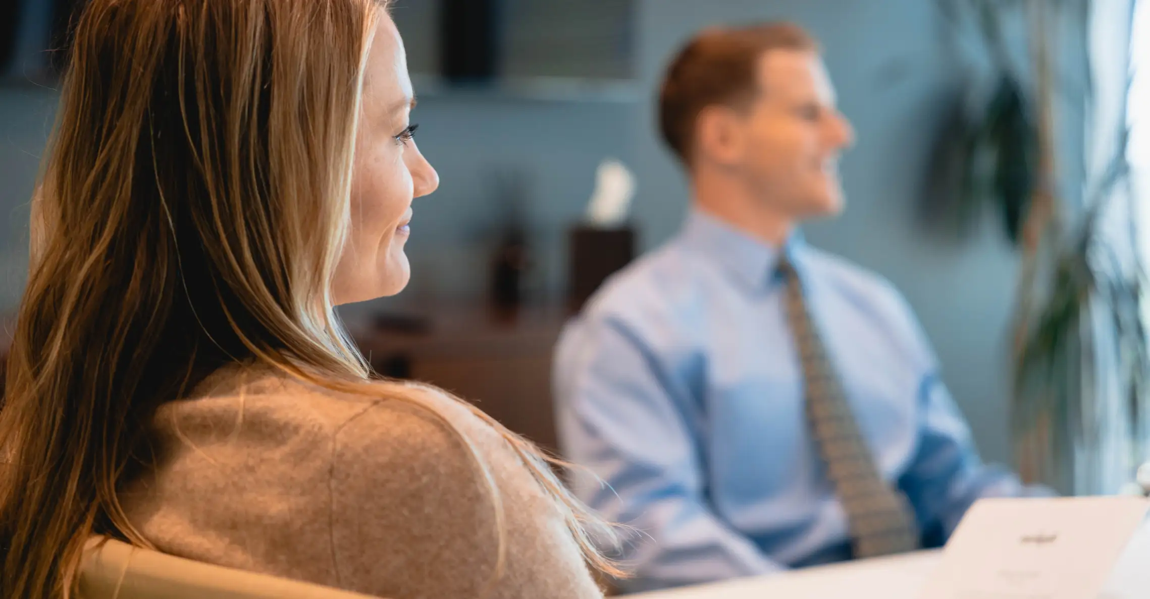 Woman and man in a business meeting sitting and smiling in an office setting.