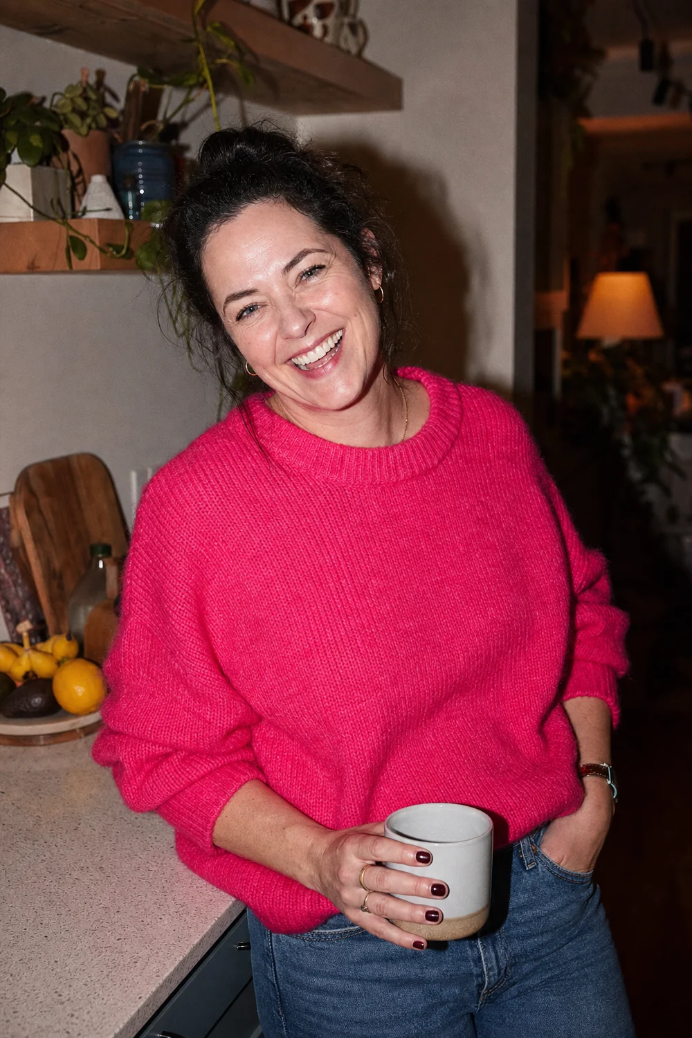 A woman in her late thirties laughing in her kitchen at home