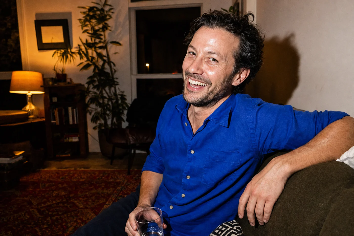 A man in his forties laughing in his living room at home