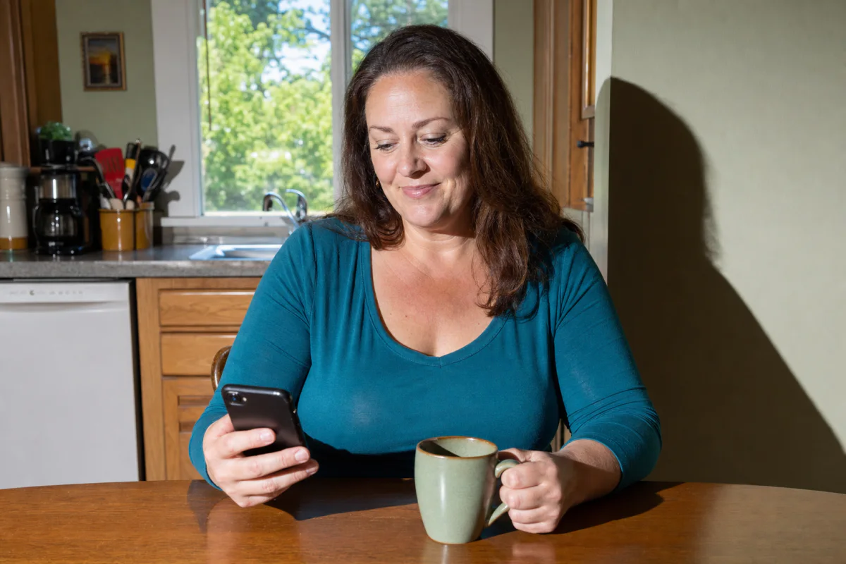 A Science and Co member checking her phone at the kitchen table