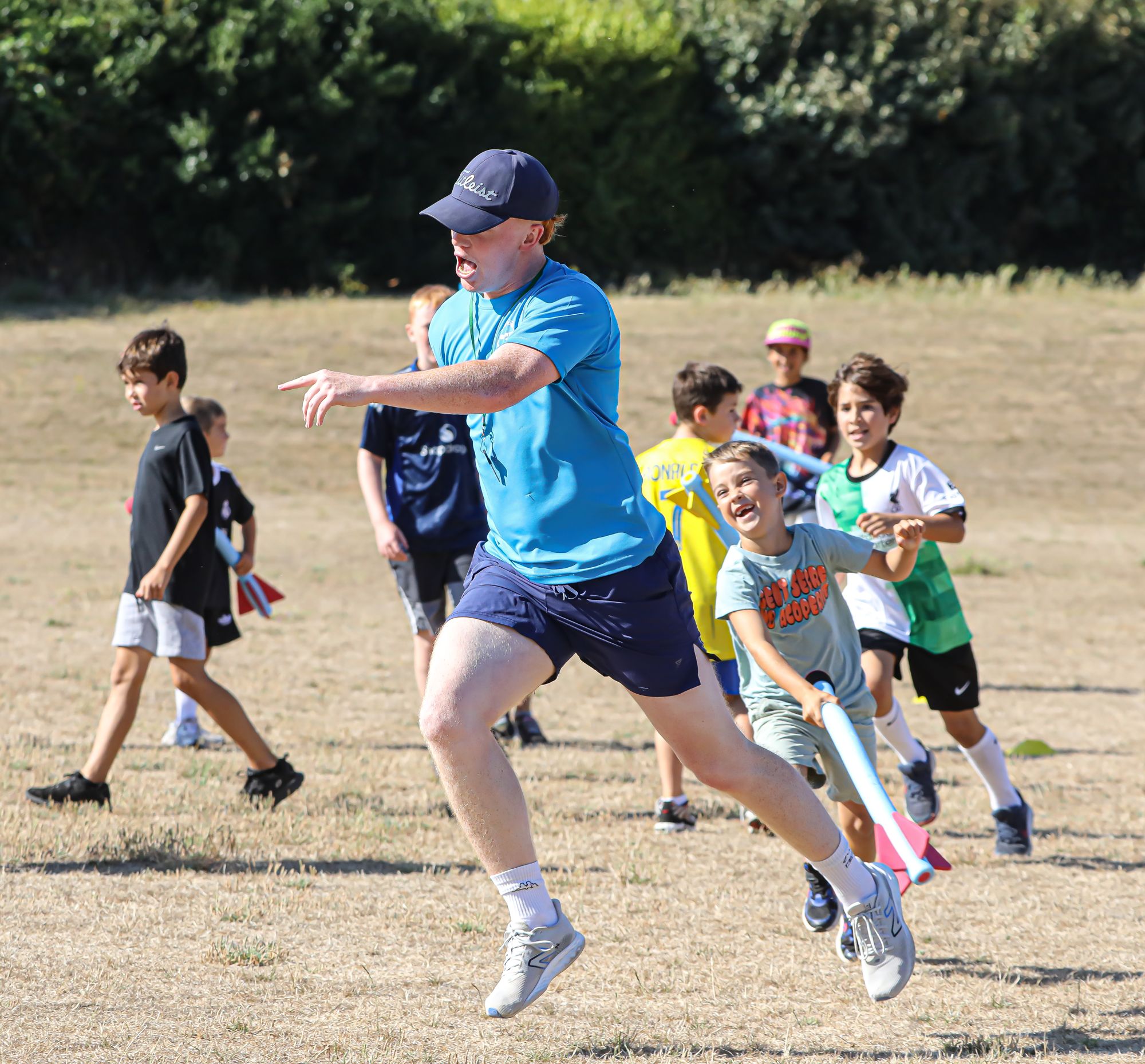 A Sports Bug coach leading an outdoor game with a group of children