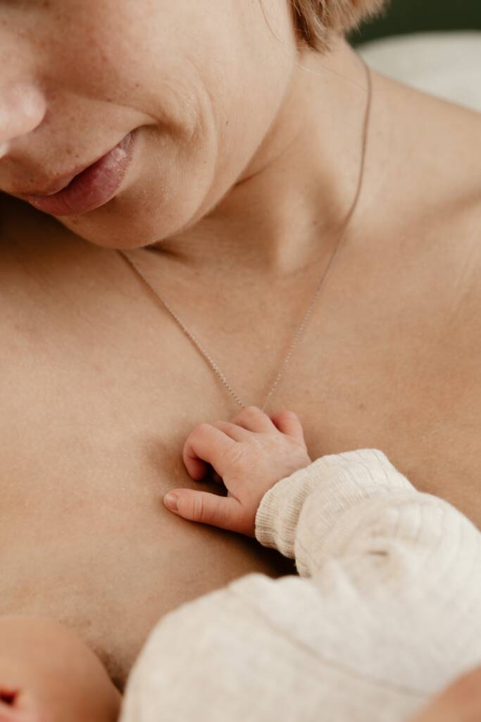 Moeder die haar baby thuis borstvoeding geeft, vastgelegd tijdens een intiem voedingsmoment.