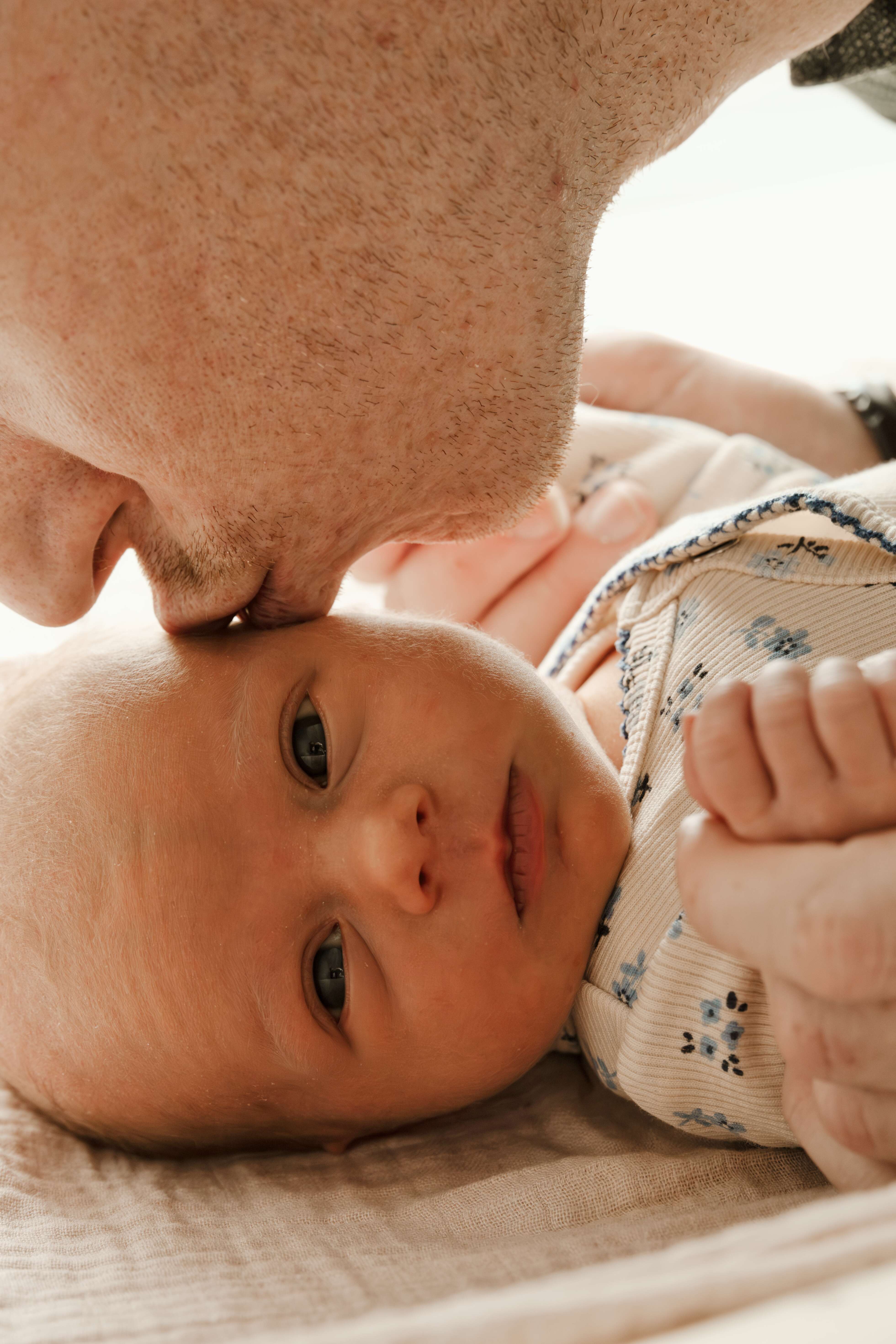 Baby met prachtige heldere ogen krijgt een kusje van haar vader