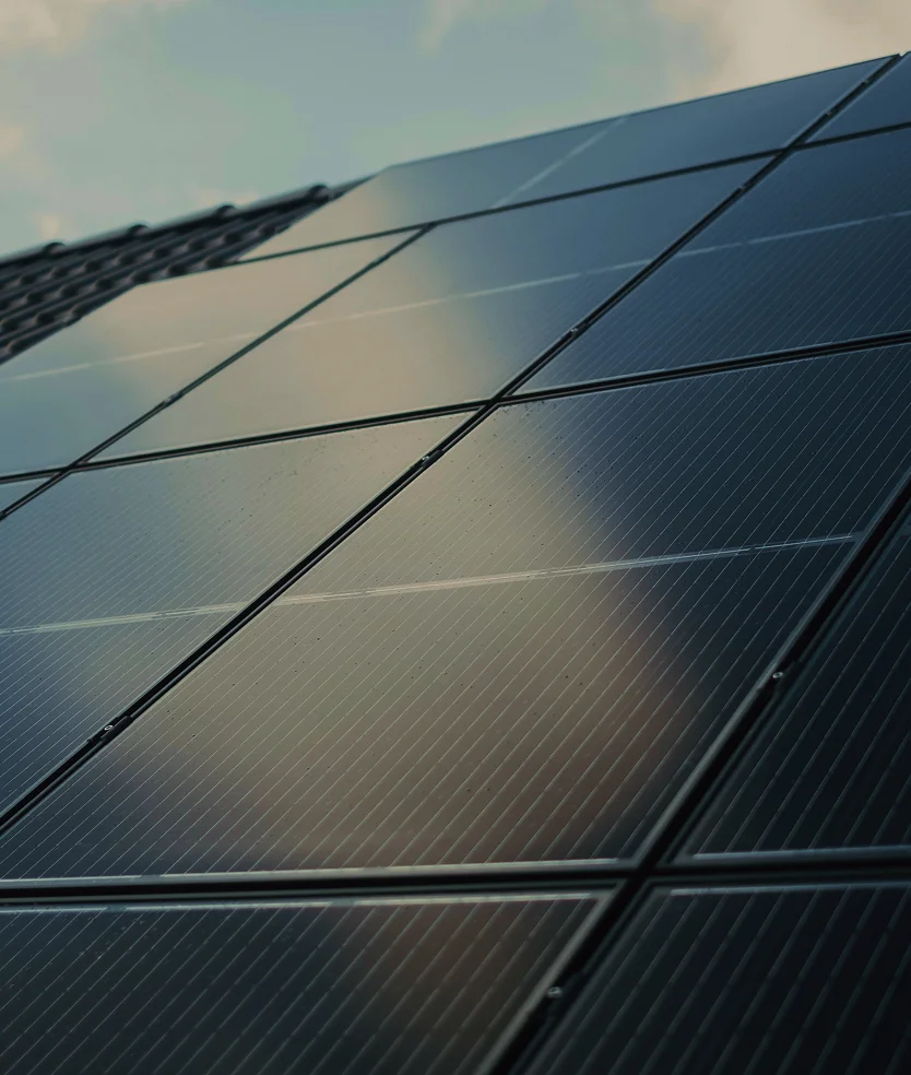 Close-up view of black solar panels on a rooftop reflecting soft daylight and the sky.