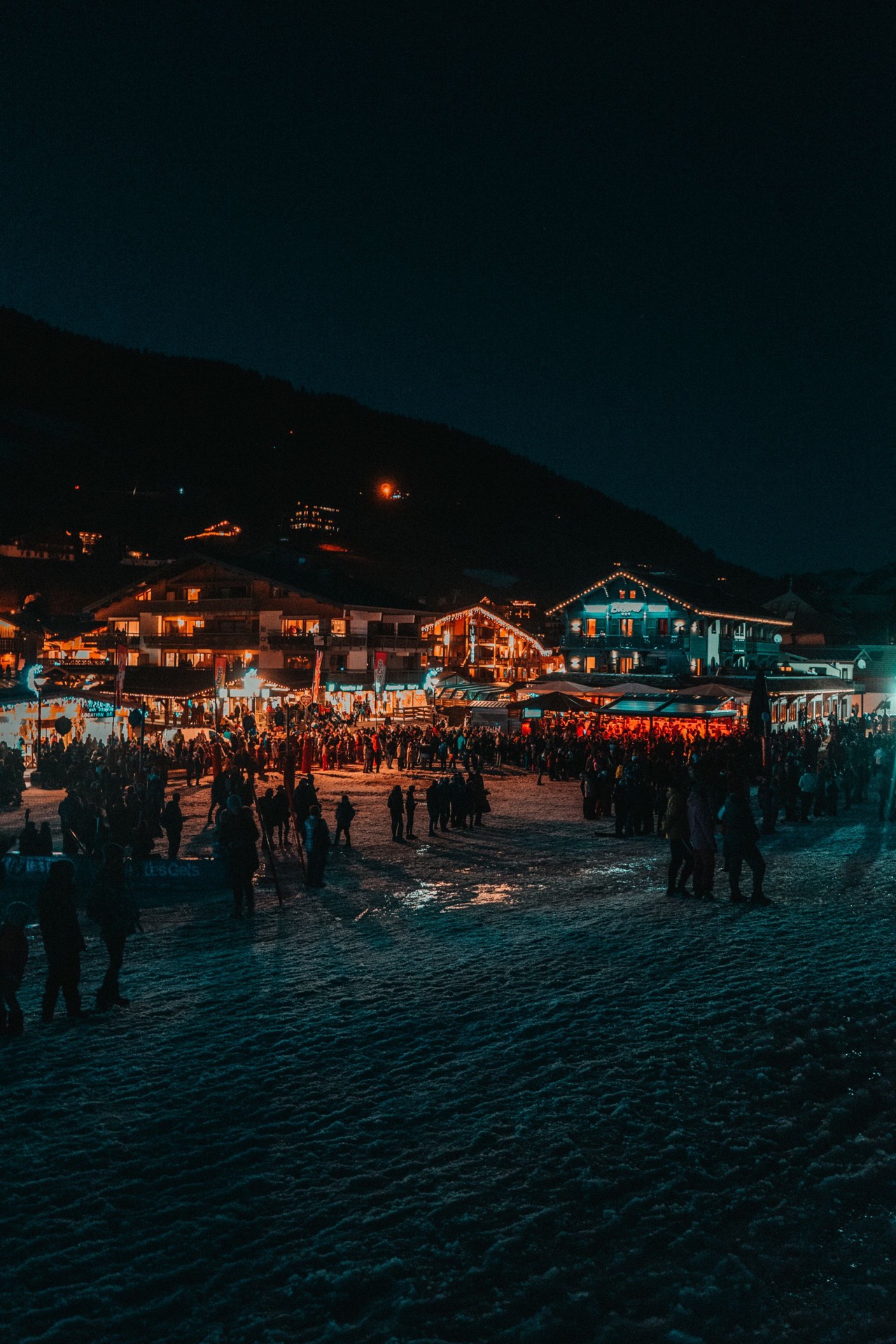 Station de ski illumin&eacute;e en soir&eacute;e, terrasses et animation au pied des pistes