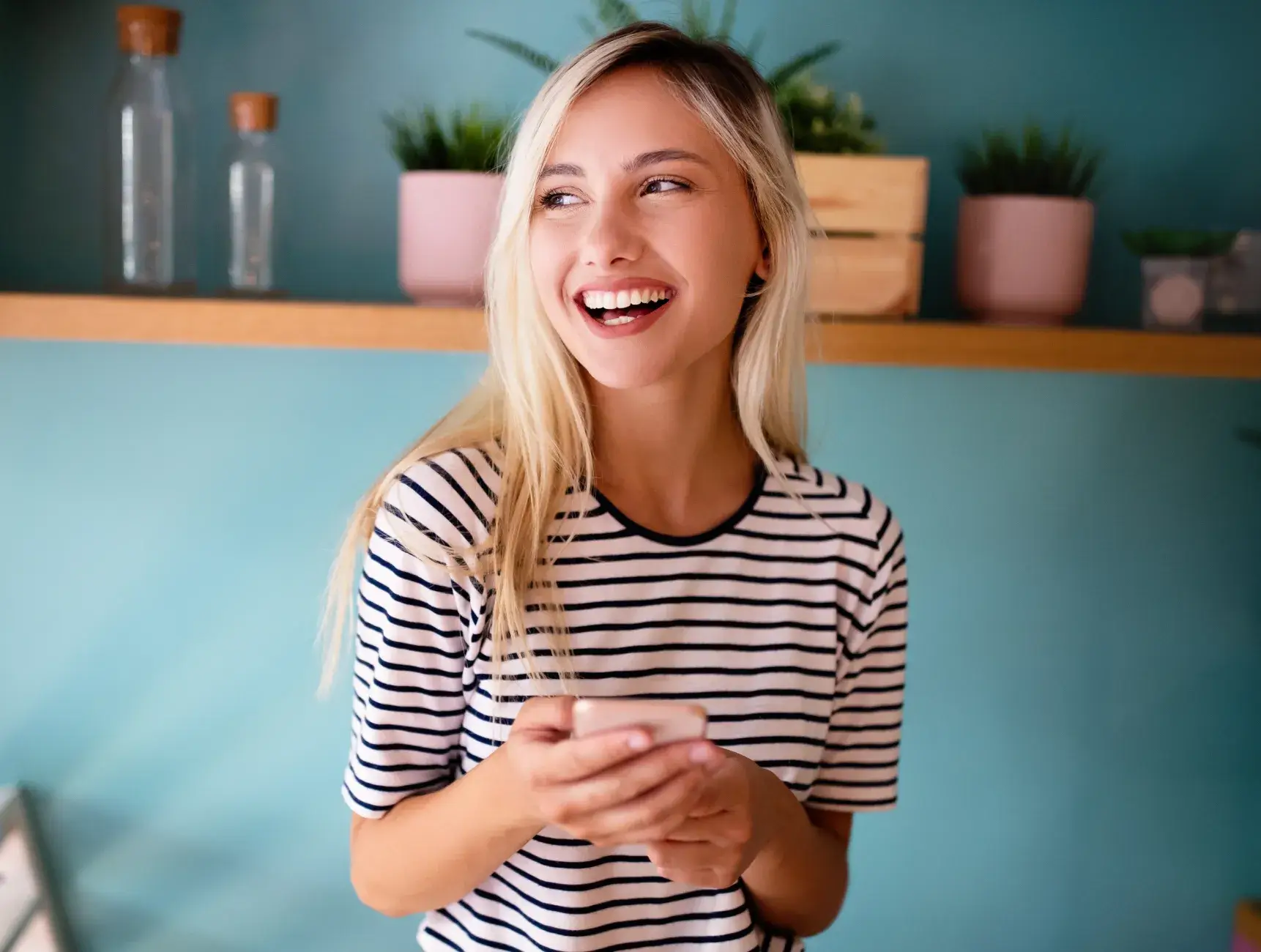 A woman laughing while holding a cell phone.