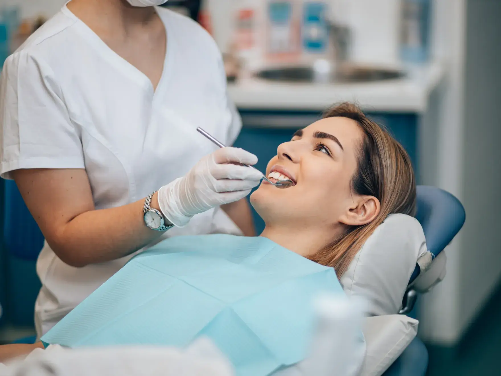A dentist examines a patient lying on a dental chair.