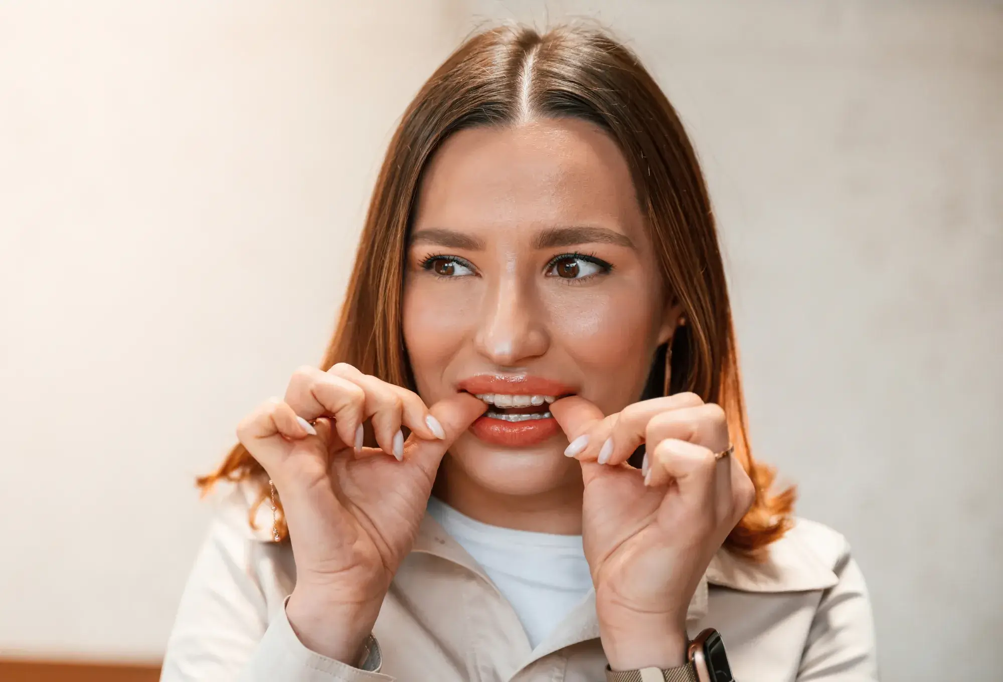 A photo of a woman with long hair flossing her teeth.