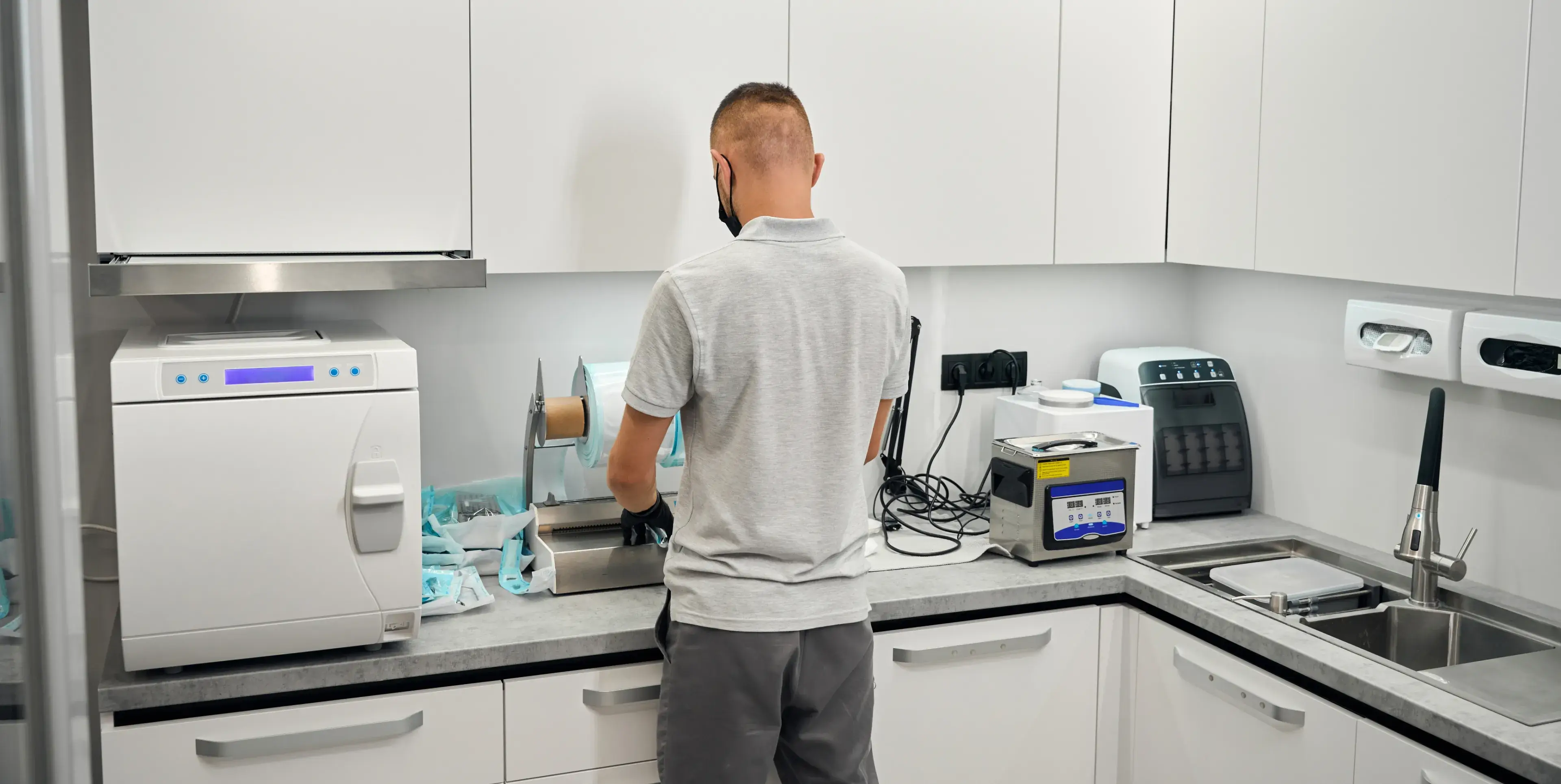 A man in a lab coats works in a white laboratory with equipment and machines on countertops.