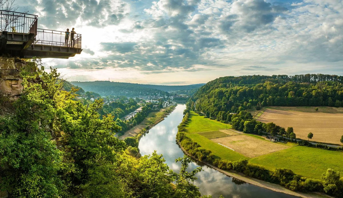 Die Aussichtsplattform des Weser-Skywalk ragt über den bewaldeten Hang, darunter windet sich die Weser durch Wald und Felder