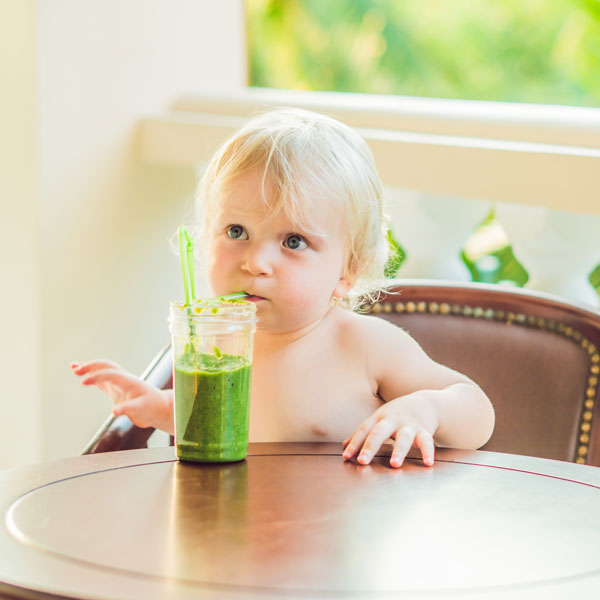 Baby drinking a green smoothie