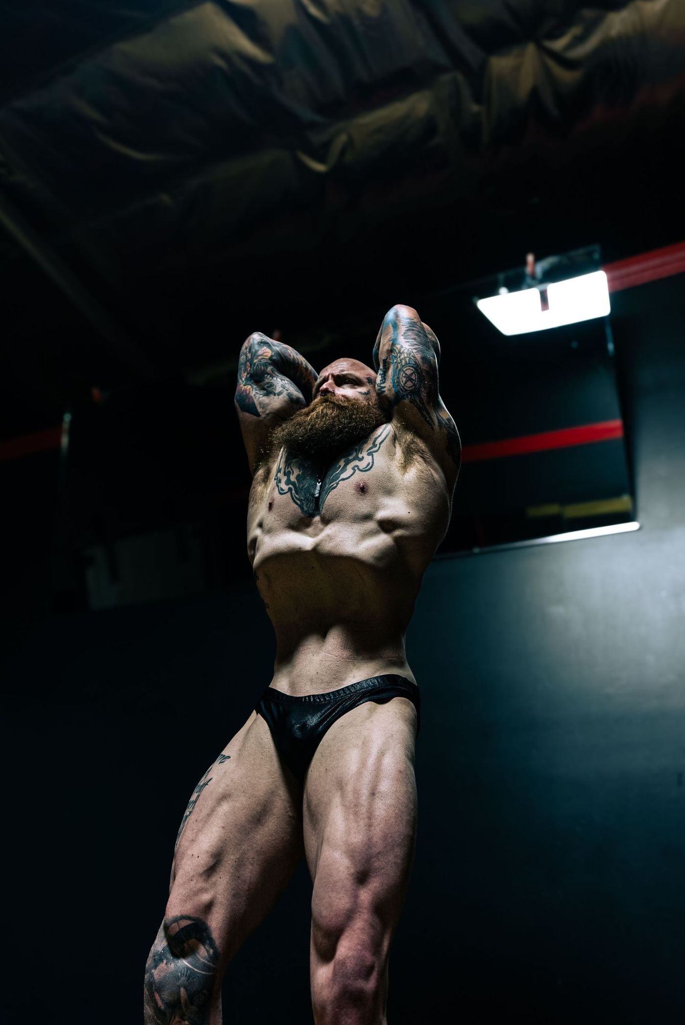 Abdominal pose with both hands behind the head, lit by one overhead panel