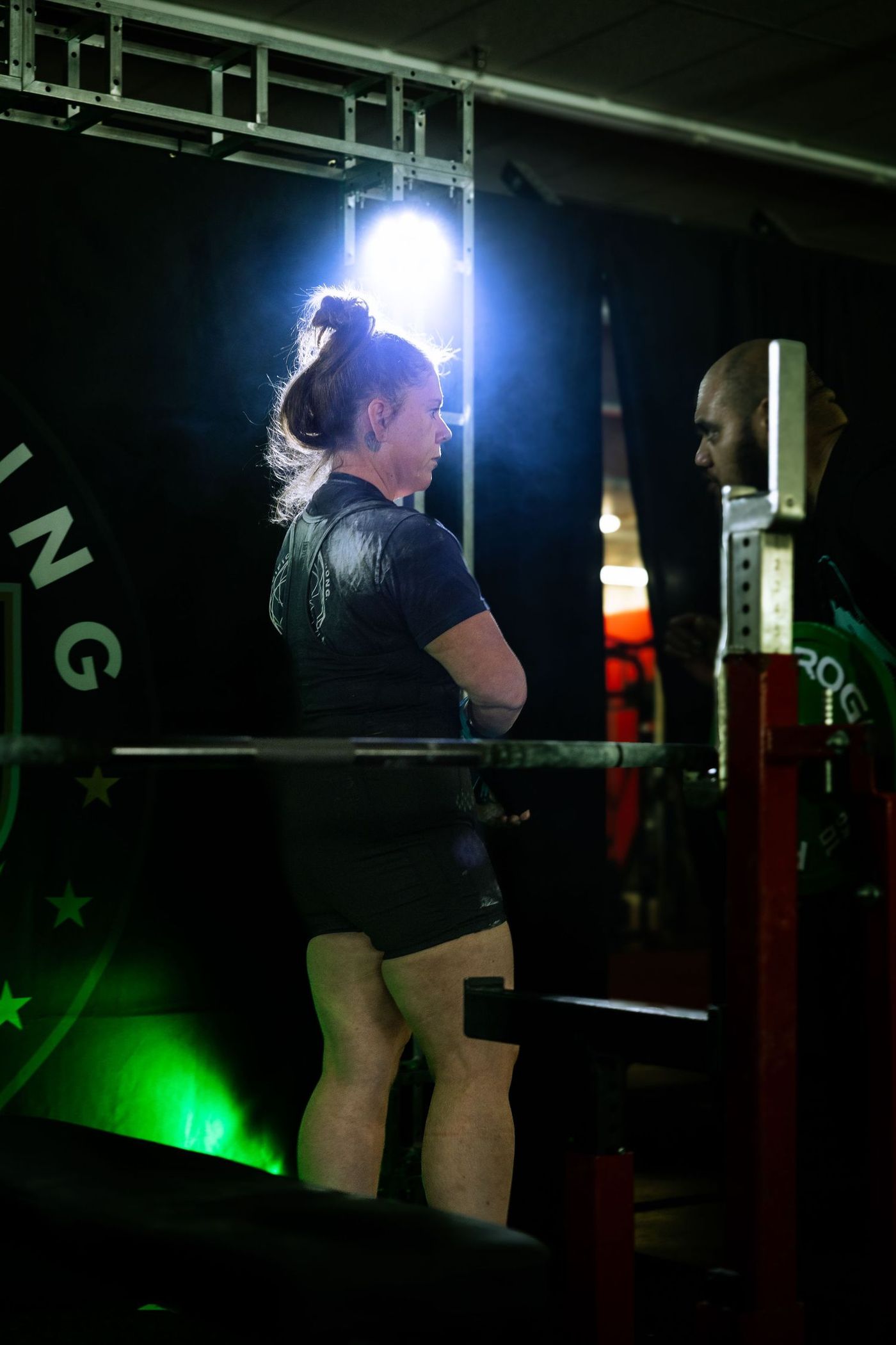 Lifter seen from behind, facing the platform under green stage light